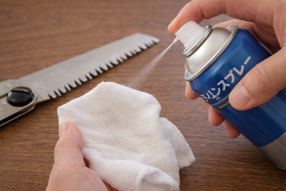 のこぎりに直接吹かずウエスにシリコンスプレーを吹き付けている様子